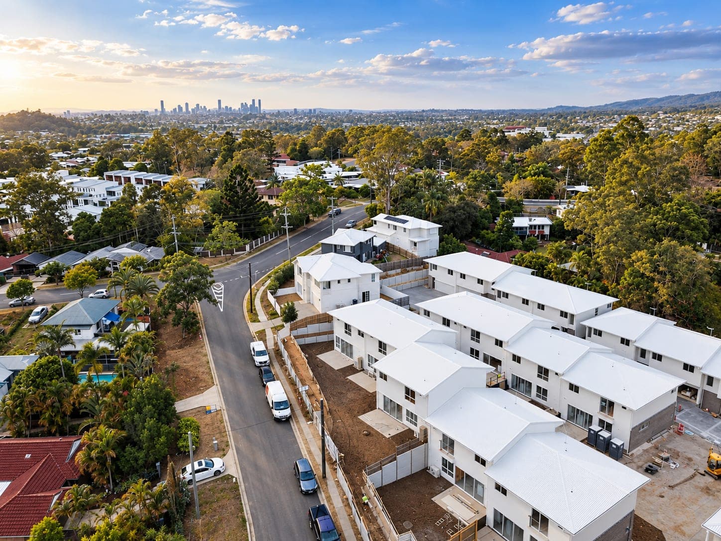 aerial view of a new white-roofed townhouse complex under construction beside an established street — SNG Engineers