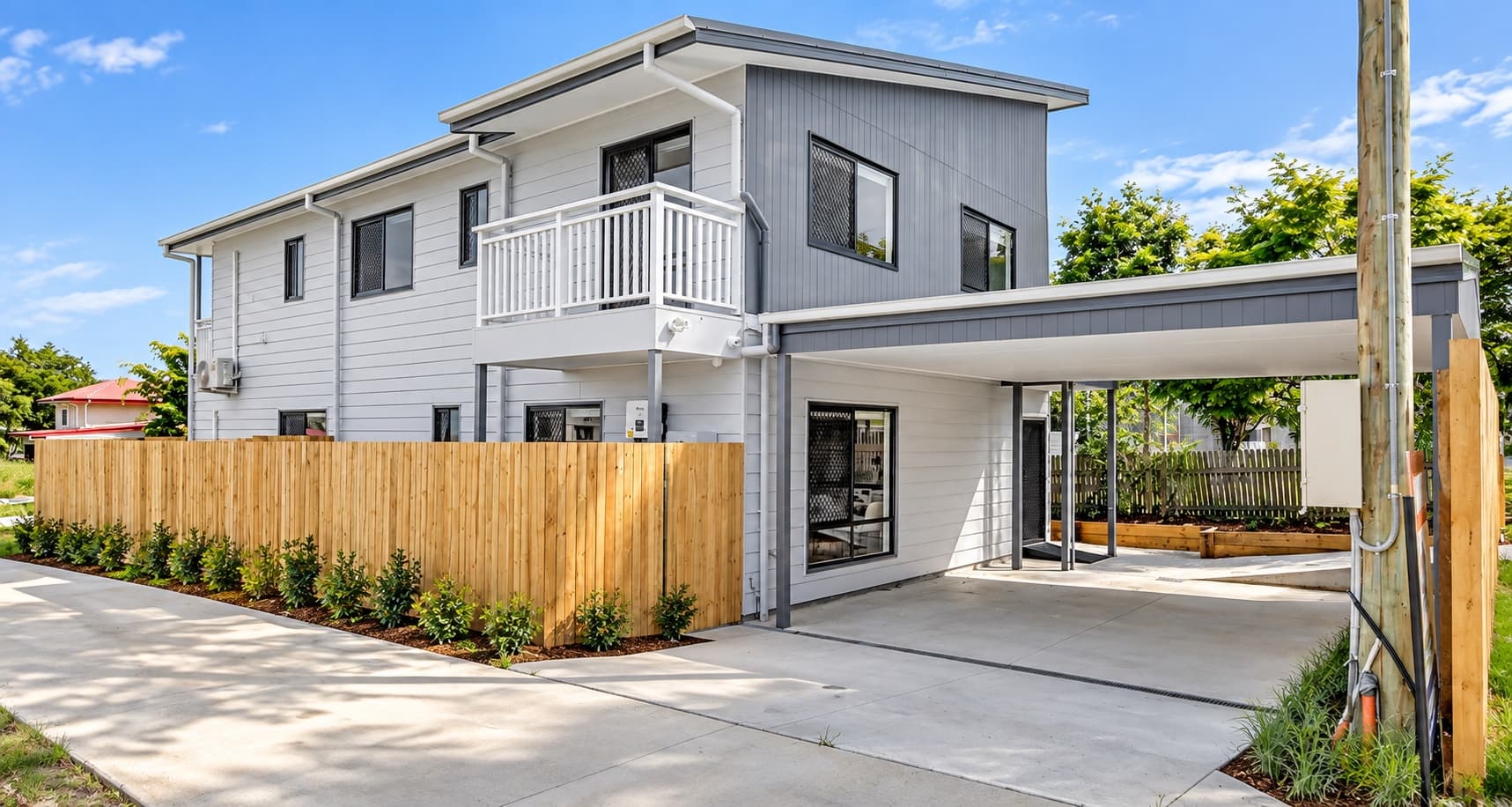 grey rendered two-storey home with white trim, dormer window, and picket front fence — SNG Engineers