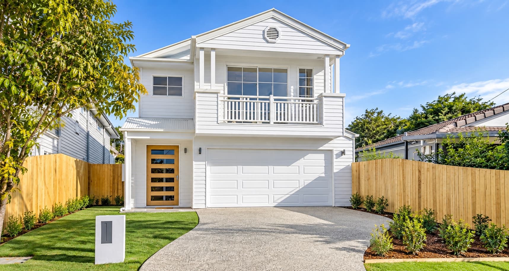 white weatherboard two-storey project home with timber front door and upper-level balcony — SNG Engineers