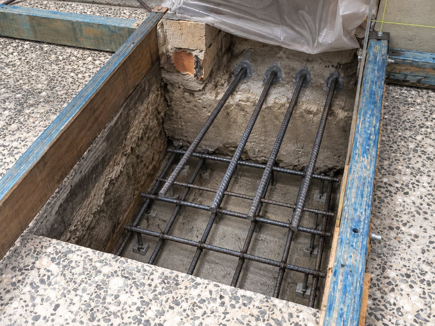 Underpinning excavation beneath an existing footing with new reinforcement and dowel bars